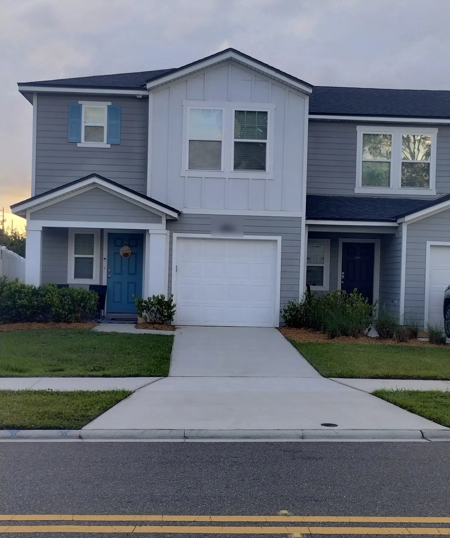 Pressure-washed driveway and walkway with a freshly cut lawn in front of a Jacksonville townhome